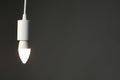 Light bulb hanging on cord against grey background, space for text Royalty Free Stock Photo