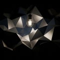 Light bulb hangs from the ceiling illuminating a geometric faceted Royalty Free Stock Photo