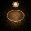 Light bulb hangs, emitting a warm glow over a textured, cracked Royalty Free Stock Photo