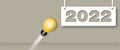 Light bulb hitting to the year 2022 on grey background. Concept for innovative business vision or resolution.
