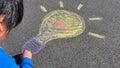 Light bulb kid drawing with colourful pastel sidewalk chalks on the pavement