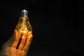 Light bulb in man hand on black background ,old technology