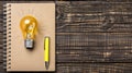 Light bulb, notepad and pencil on table. Concept of idea generation and creativity. Writing stories and drawing. Royalty Free Stock Photo