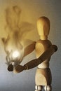 a light bulb shines in the hands of the wooden figure, the warmth of the bulb makes the wood of the doll smoke