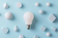 A light bulb surrounded by various geometric shapes on a blue background Royalty Free Stock Photo