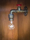 Light bulb at a water pipe with a red rotary velve Royalty Free Stock Photo
