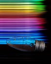 The light bulb is wet on the table and on the back are multi-colored stripes in the form of a rainbow. art photo Royalty Free Stock Photo