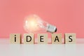 Light bulb on wooden cube blocks with word ideas, thinking creative genius innovation knowledge successful. Royalty Free Stock Photo