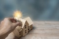 A light bulb and a wooden house model from a model on a wooden table Royalty Free Stock Photo
