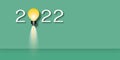 Light bulb in the year 2022 on green background. Concept for innovative business vision or resolution.