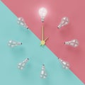 Light bulbs glowing one different idea clock concept on cross pastel pink and light blue background Royalty Free Stock Photo