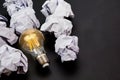 Light bulbs glows orange and crumpled paper on black background. Good idea, creativity and inspiration concept. Royalty Free Stock Photo