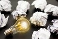 Light bulbs glows orange and crumpled paper on black background. Good idea and inspiration concept. Royalty Free Stock Photo