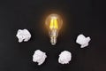 Light bulbs glows orange and crumpled paper on black background. Good idea and inspiration concept Royalty Free Stock Photo
