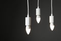 Light bulbs hanging on cords against grey background, space for text Royalty Free Stock Photo