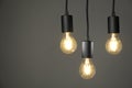 Light bulbs hanging on cords against grey background, space for text Royalty Free Stock Photo
