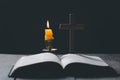 Light candle with holy bible and cross or crucifix on old wooden background in church.Candlelight and open book on vintage wood Royalty Free Stock Photo