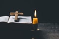 Light candle with holy bible and cross or crucifix on old wooden background in church.Candlelight and open book on vintage wood Royalty Free Stock Photo