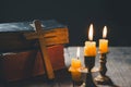 Light candle with holy bible and cross or crucifix on old wooden background in church.Candlelight and open book on vintage wood Royalty Free Stock Photo