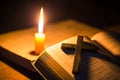 Light candle with holy bible and cross or crucifix on old wooden background in church.Candlelight and open book on vintage wood Royalty Free Stock Photo