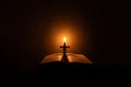 Light candle with holy bible and cross or crucifix on old wooden background in church.Candlelight and open book on vintage wood Royalty Free Stock Photo