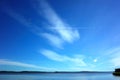 Small airplane flying with trail on background of beautiful light clouds on blue sky Royalty Free Stock Photo