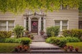 Light colored brick house with ornate entranceway and beautiful landscaping around sidewalk and steps leading up - framed by