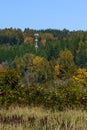 Light colored mobile phone tower with antennas on a hillside with evergreen trees and fall color deciduous trees, and clear blue s Royalty Free Stock Photo