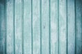 Light colored timber fence with peeling paint. Shabby decrepit wooden boards. Wood lamellas. Blue rough painted planks surface.