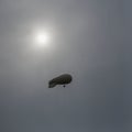 Light coloured blimp, hot air airship in grey sky. Rainy day, unearthly fantastic, but a real landscape. Inflatable