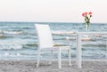 A light composition with white wooden table and chair on the sea or ocean. Blurred background. Royalty Free Stock Photo