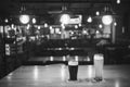 Light and dark beer in glasses on a table in a bar under vintage lamps, black and white frame. Royalty Free Stock Photo