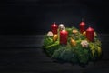 Light in the dark on first advent, natural green wreath with red candles, one is burning, Christmas decoration and cookies, dark