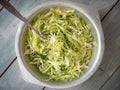 Light diet salad of cabbage with orages, thin slices in a metal cup with a fork, on a wooden table