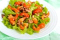 Light dietary spicy salad of lettuce, seafood crawfish, shrimp and walnuts on a white wooden background.