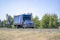 Light duty small semi truck with covered box trailer driving on the narrow road for delivery loaded goods Royalty Free Stock Photo