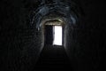 Light in the end of dark tunnel. Brick walls and concrete stairs to the light from the dungeon