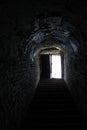 Light in the end of dark tunnel. Brick walls and concrete stairs to the light from the dungeon