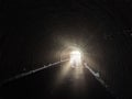 Light at end of round flooded sewer tunnel. Exit from sewer system