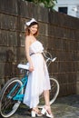 Light female is leaning on retro bicycle against dark wall Royalty Free Stock Photo