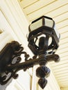 A light fixture hanging on the outside wall of the white house black metal Royalty Free Stock Photo