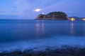 Light of Getaria lighthouse and fullmoon over the sea at night.