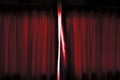 The light go through the about open dark red color curtain of the stage before performing.