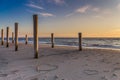 The light of golden hour at the beach with wooden piles and hearts drawings in the sand