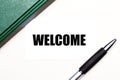 On a light gray background lies a pen, a green notebook and a white card with the text WELCOME. Business concept Royalty Free Stock Photo