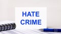 On a light gray background, a notebook, a blue pen and a sheet of paper with the text HATE CRIME. Business concept Royalty Free Stock Photo
