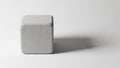 Light gray cube with textured surfaces sits on a smooth white Royalty Free Stock Photo