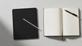 On a light gray surface beside an open notebook with blank pages. A Royalty Free Stock Photo