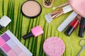 On a light green background and palm leaves, scattered in a pink cosmetic bag makeup items, brush, nail Polish, lipstick, powder, Royalty Free Stock Photo