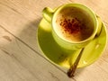 Light green coffee cup on white wooden table with a cappucchino and cacao powder Royalty Free Stock Photo